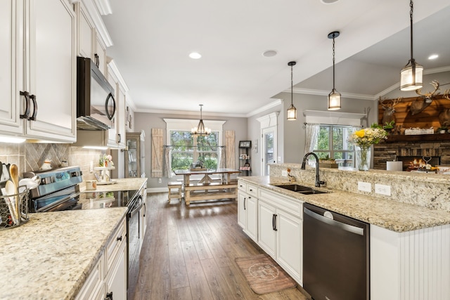 kitchen with a wealth of natural light, dark wood-type flooring, appliances with stainless steel finishes, and pendant lighting