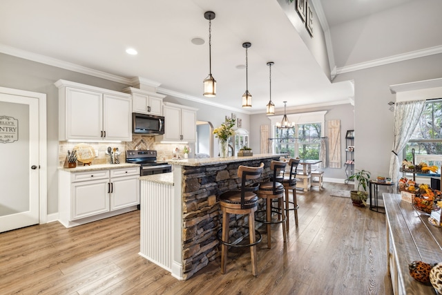 kitchen with stainless steel appliances, white cabinetry, an island with sink, and light hardwood / wood-style flooring