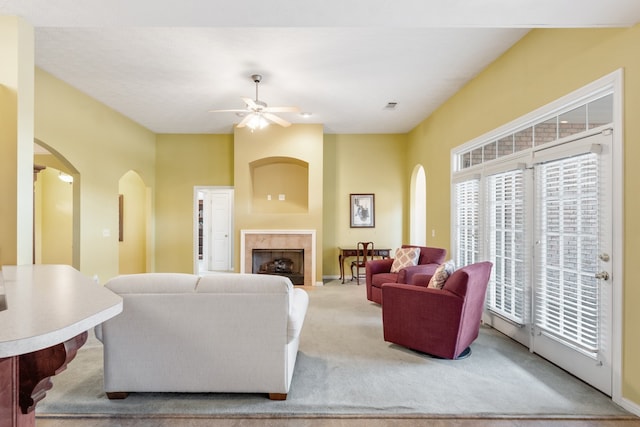 living room with light colored carpet, ceiling fan, and a tile fireplace