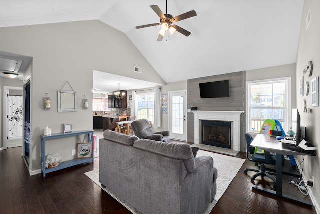 living room with dark wood-type flooring, ceiling fan with notable chandelier, plenty of natural light, and high vaulted ceiling