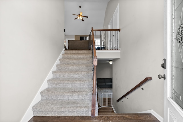 stairs with high vaulted ceiling, hardwood / wood-style floors, and ceiling fan