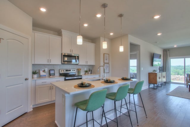 kitchen with an island with sink, white cabinets, a healthy amount of sunlight, and appliances with stainless steel finishes