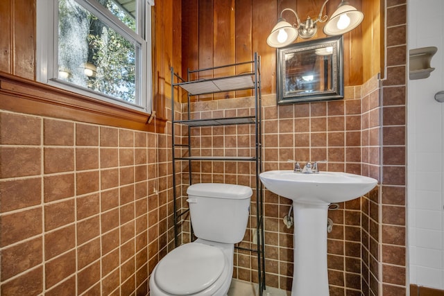 bathroom with toilet and tile walls