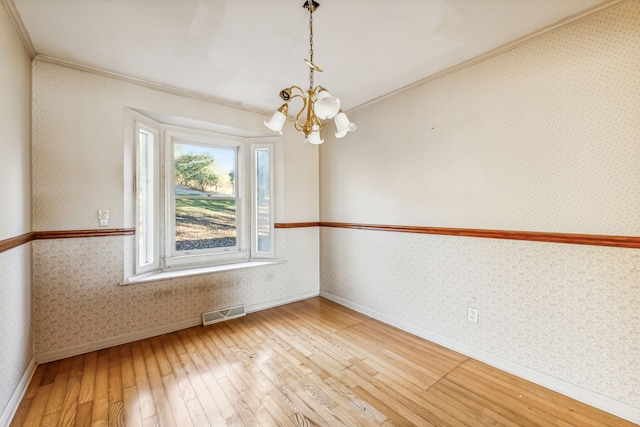 unfurnished room with hardwood / wood-style floors, a notable chandelier, and ornamental molding