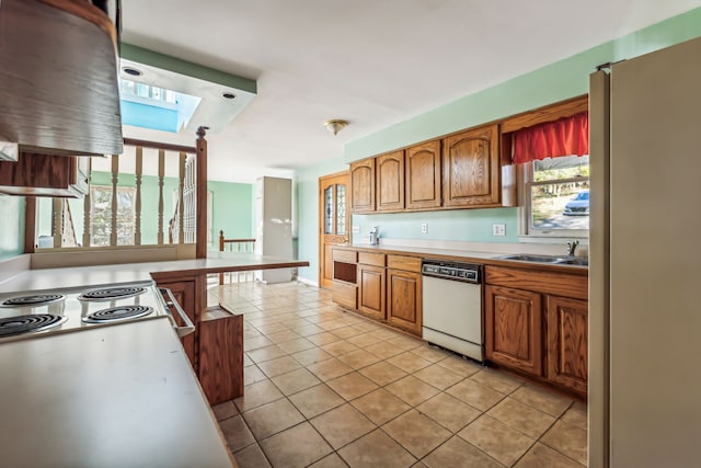 kitchen featuring dishwasher, sink, stainless steel refrigerator, and light tile patterned flooring