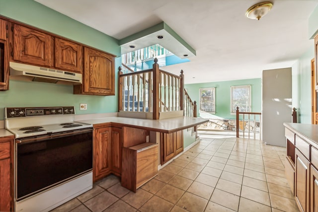 kitchen featuring white electric stove, a wealth of natural light, and light tile patterned floors