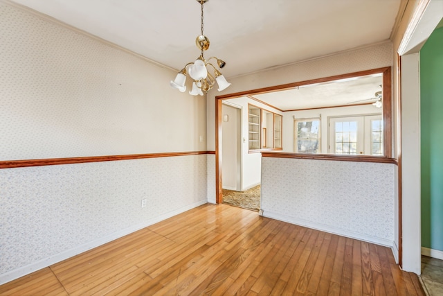 spare room with hardwood / wood-style flooring, a chandelier, and crown molding