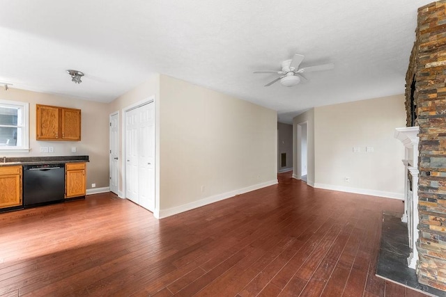 unfurnished living room with ceiling fan, a fireplace, and dark hardwood / wood-style floors