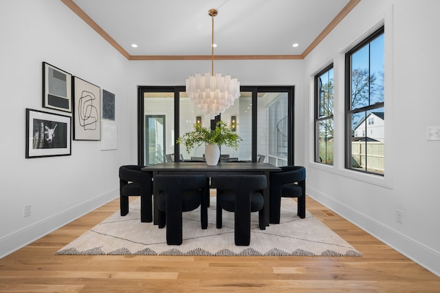 dining room with hardwood / wood-style floors, ornamental molding, and an inviting chandelier