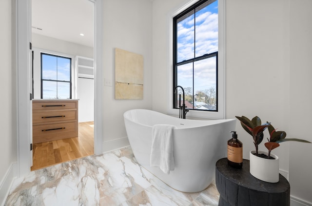 bathroom with a tub to relax in and hardwood / wood-style floors