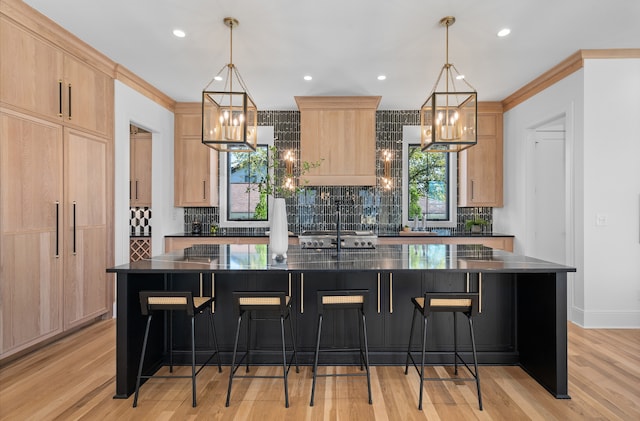 kitchen featuring a center island with sink, light brown cabinets, and pendant lighting