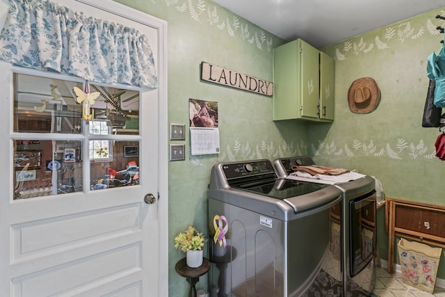 clothes washing area featuring separate washer and dryer and cabinets