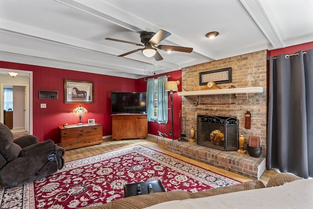 living room featuring a fireplace, beam ceiling, light hardwood / wood-style flooring, and ceiling fan