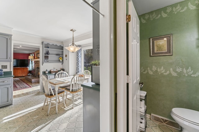 dining area featuring light wood-type flooring and crown molding