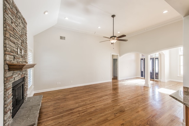 unfurnished living room with wood-type flooring, ornamental molding, a fireplace, lofted ceiling, and ceiling fan