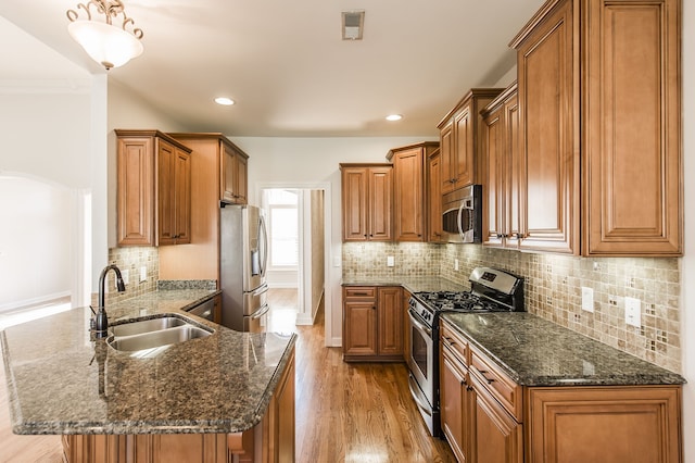 kitchen featuring tasteful backsplash, appliances with stainless steel finishes, sink, and light hardwood / wood-style floors