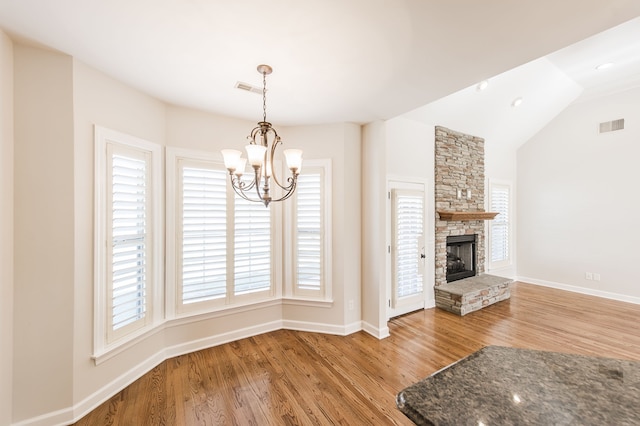 interior space featuring a fireplace, a wealth of natural light, wood-type flooring, and a notable chandelier