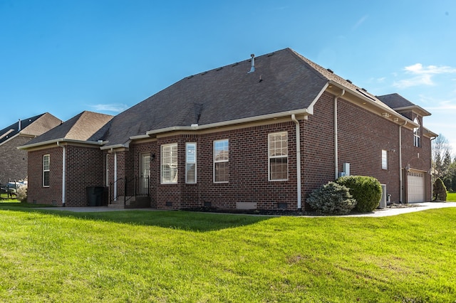 rear view of property with a garage and a lawn