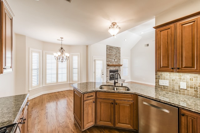 kitchen featuring a fireplace, stainless steel appliances, sink, a chandelier, and light hardwood / wood-style flooring