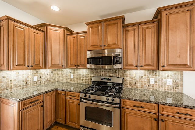 kitchen featuring dark stone countertops, decorative backsplash, and stainless steel appliances