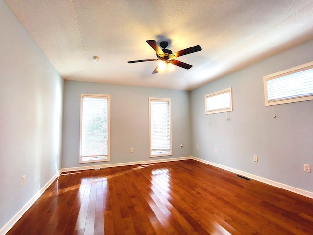 spare room with a wealth of natural light, wood-type flooring, ceiling fan, and a textured ceiling