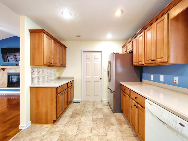 kitchen with light hardwood / wood-style floors, a textured ceiling, white dishwasher, and stainless steel fridge