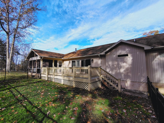 back of property with a deck, a lawn, and a sunroom