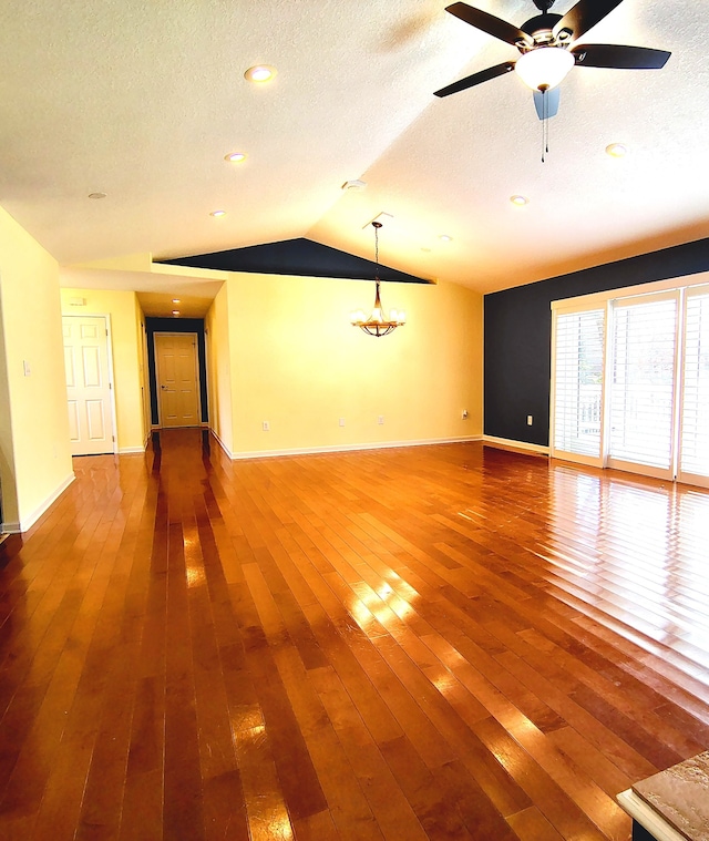 empty room with wood-type flooring, a textured ceiling, ceiling fan, and vaulted ceiling