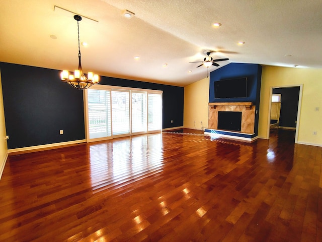 unfurnished living room featuring ceiling fan with notable chandelier, dark hardwood / wood-style flooring, vaulted ceiling, a textured ceiling, and a fireplace