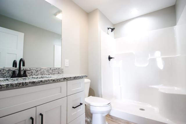 bathroom featuring a shower, vanity, and toilet