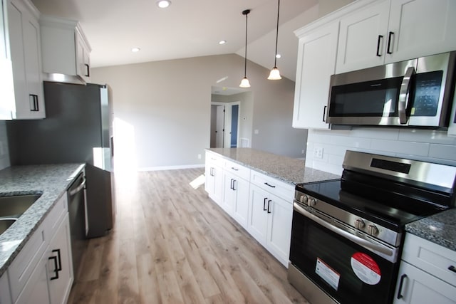 kitchen featuring stainless steel appliances, lofted ceiling, white cabinets, decorative backsplash, and decorative light fixtures