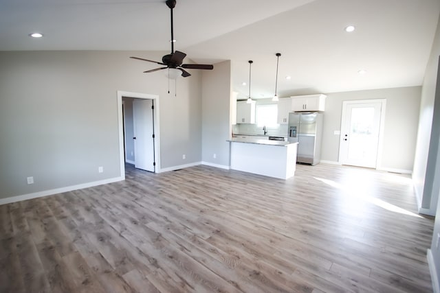 unfurnished living room with light hardwood / wood-style floors, ceiling fan, sink, and lofted ceiling