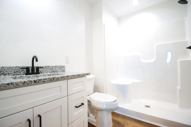 bathroom featuring vanity, hardwood / wood-style flooring, toilet, and a shower