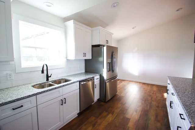 kitchen featuring white cabinetry, sink, appliances with stainless steel finishes, light stone countertops, and dark wood-type flooring