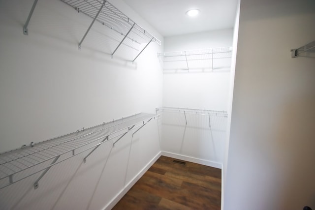 walk in closet with dark hardwood / wood-style floors