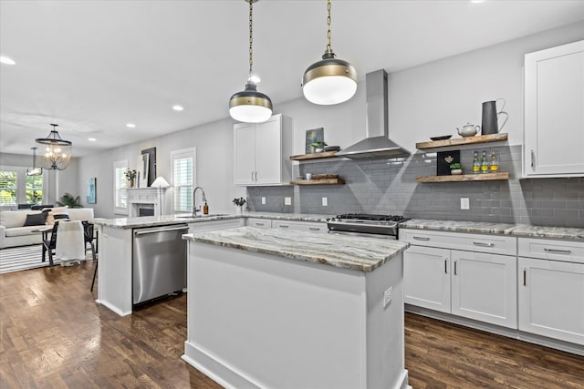 kitchen featuring white cabinetry, wall chimney range hood, appliances with stainless steel finishes, dark hardwood / wood-style floors, and a center island