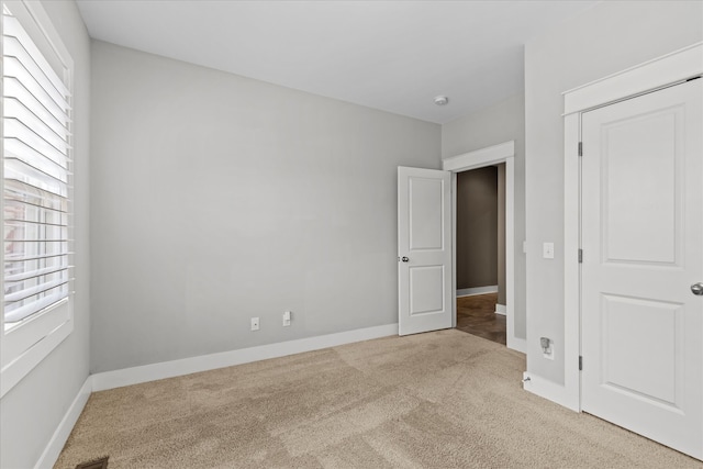 unfurnished bedroom featuring light colored carpet and multiple windows