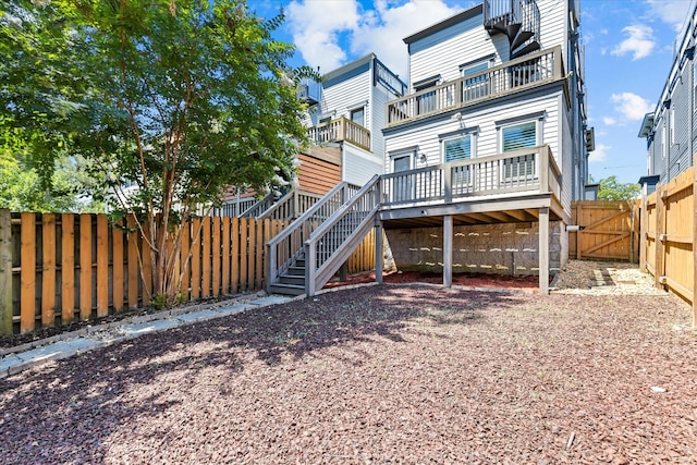 back of house with a wooden deck and a balcony