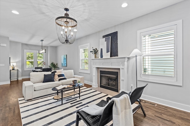 living room with hardwood / wood-style flooring, a tile fireplace, and an inviting chandelier