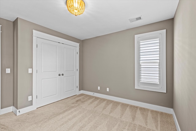 unfurnished bedroom featuring light carpet and a closet