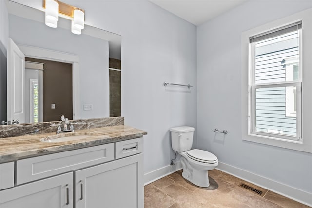 bathroom with a wealth of natural light, vanity, tile patterned floors, and toilet