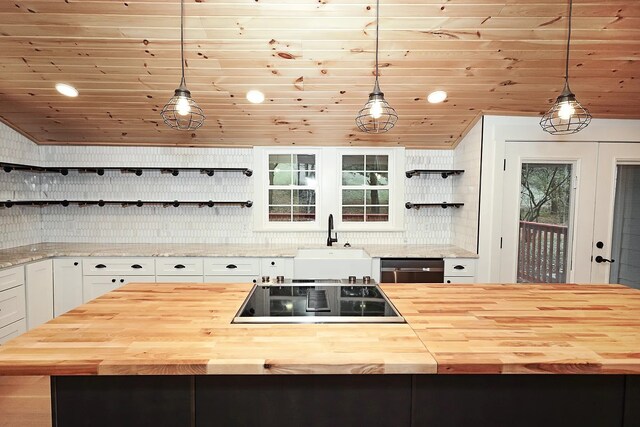 kitchen featuring white cabinets, wooden counters, decorative light fixtures, and a kitchen island