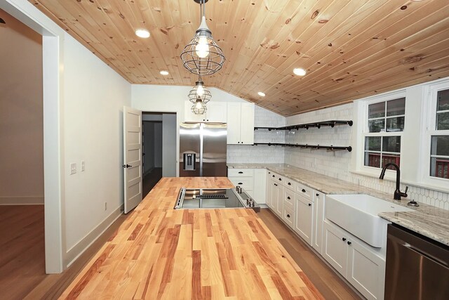 kitchen featuring white cabinetry, appliances with stainless steel finishes, butcher block counters, and decorative light fixtures