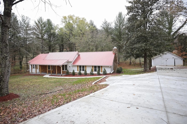 ranch-style house featuring covered porch, a garage, an outdoor structure, and a front lawn