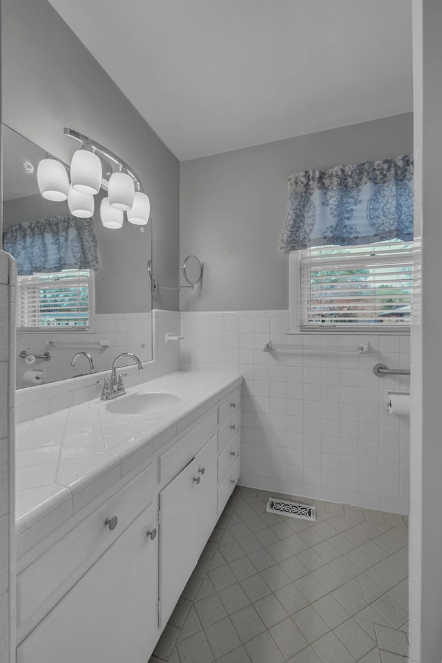 bathroom with tile patterned flooring, vanity, plenty of natural light, and tile walls