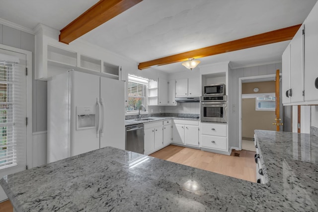 kitchen with a wealth of natural light, light stone counters, white cabinets, and stainless steel appliances