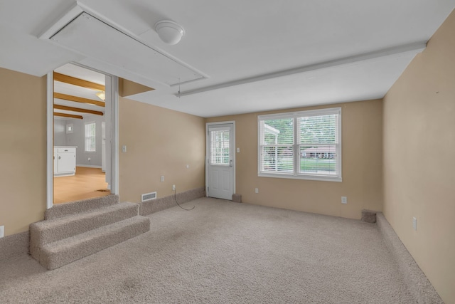 carpeted empty room featuring beamed ceiling