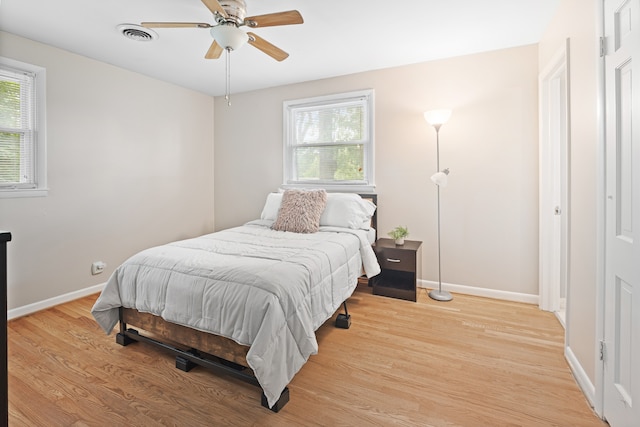 bedroom featuring light wood-type flooring, multiple windows, and ceiling fan