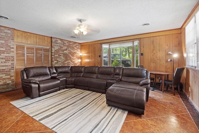 tiled living room with brick wall, a textured ceiling, ceiling fan, and wood walls