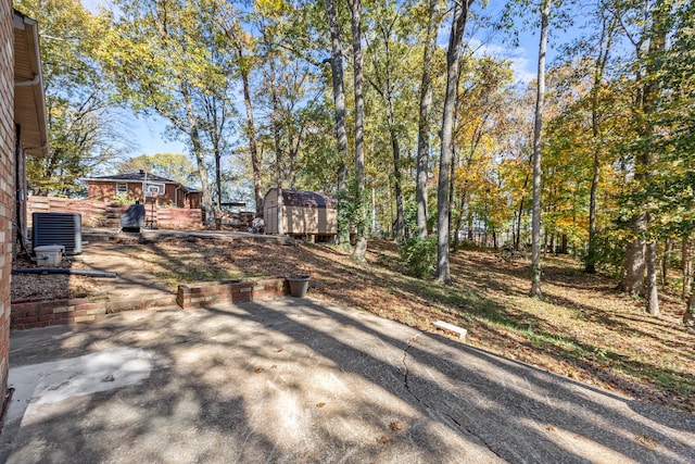 view of yard with central AC unit, a shed, and a patio